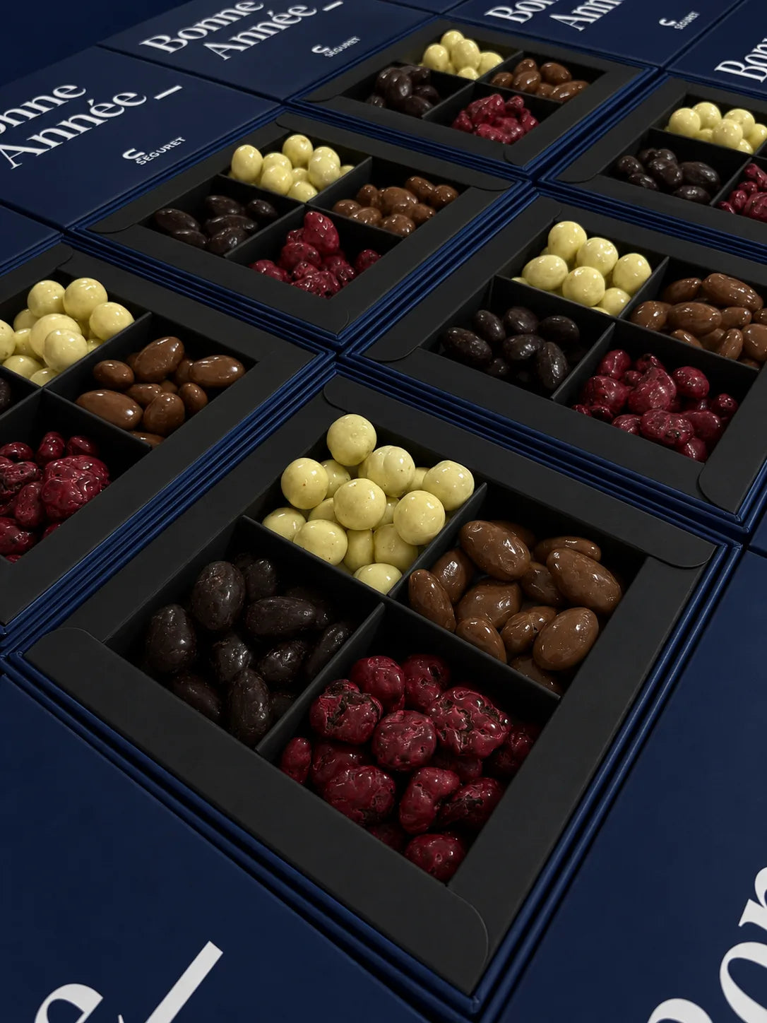 Carrés Astral de fruits enrobés de chocolat dans des boîtes bleues « Bonne Année » au nom du client